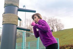 young woman training in combat sport alone on the sports ground with traditional dummies photo