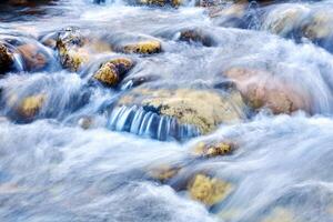 cascade of waterfalls of a mountain river among the boulders, the water is blurred in motion photo