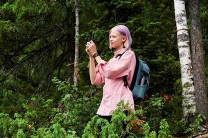 teenage girl hiker in the forest takes a photo using a smartphone