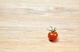 lone cherry tomato on a wooden table surface photo