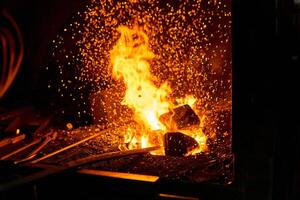 herrero horno con ardiente fuego y forjar herramientas acostado cerca foto