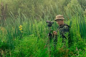 birdwatcher records the results of the observations while standing among the tall grass in the wetland photo