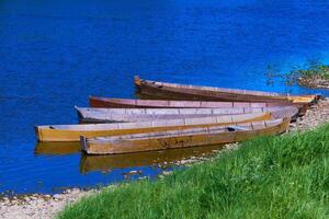 traditional wooden flat-bottomed boats on the river bank, rural landscape photo