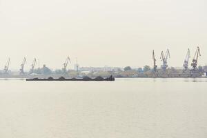 industrial río paisaje acuático con seco carga barcaza y carga terminal en Mañana niebla foto