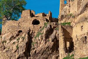 ruins of an old stone house under a tree in the historical abandoned village of Gamsutl in Dagestan photo