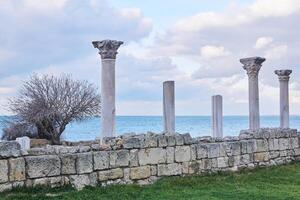 ruins of antique greek temple with columns on the seashore photo