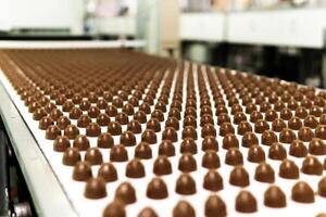 chocolate toppings on the conveyor of a confectionery factory close-up photo