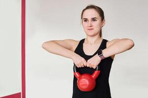 young woman is training with kettlebell in gym photo