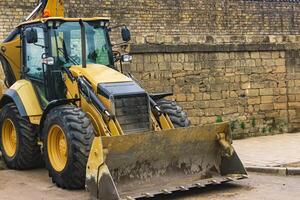 wheeled bucket loader next to a brick wall photo