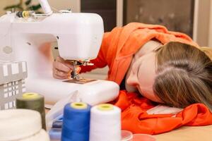 female seamstress tries to set the needle in a sewing machine photo