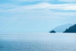 misty seascape with distant mountainous shores in midday haze photo