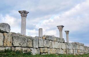 ruins of the wall of antique greek temple with columns against the sky photo