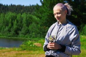 girl with a bouquet of wildflowers in nature by the river photo