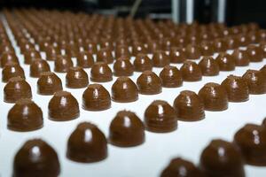 chocolate toppings on the conveyor of a confectionery factory close-up photo