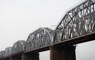 several spans of a railway truss bridge against a cloudy sky photo