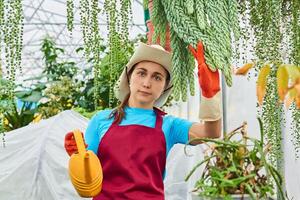 young woman with a watering can works in a greenhouse photo