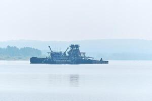 floating sand mining plant on the river in the morning fog photo