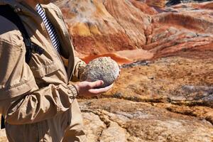 paleontologist holding a dinosaur egg in his hands on the background of the desert, close-up photo