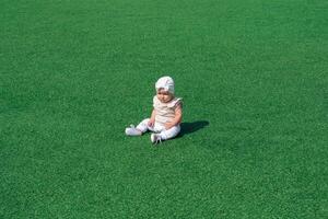 bebé niñito sentado en el medio de un verde césped foto