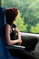 young woman in a moving suburban train looks out the window photo