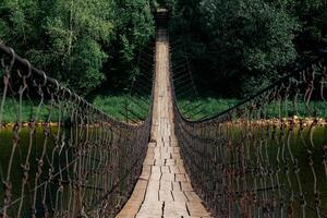 old suspension bridge over the river goes into perspective photo