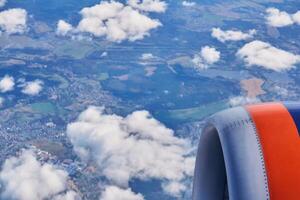 view from the window of a passenger plane, you can see a fragment of the engine and blurred earth in the distance photo