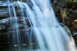 waterfall jets in a mountain stream between rocks, the water is blurred in motion photo