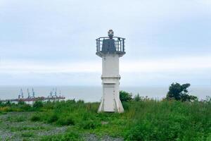 automatic lighthouse with sector light on a high cape above the sea harbor photo