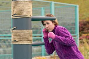 young woman practicing martial arts alone on the sports ground with traditional dummies photo