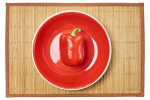 red bell pepper on a red plate on a cane place mat photo