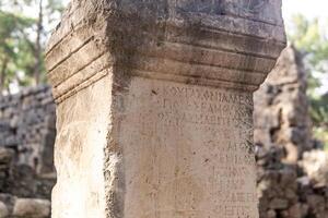 half-erased antique inscription on a stone among the ruins of the ancient city of Phaselis, Turkey photo