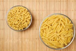 two bowls of dried pasta on a cane tablecloth photo