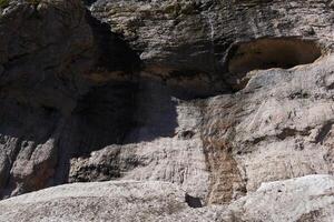 rock wall with streams of water flowing down it over the melting glacier in the mountains photo