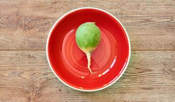 big green radish on a red plate on a wooden tabletop photo