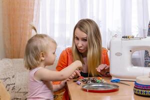 seamstress woman interrupted work and plays with little daughter photo