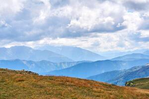 autumn mountain landscape on a cloudy day with blue mountain ranges in the distance photo