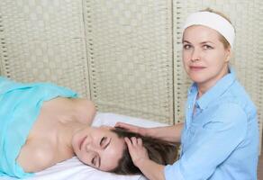 joven bonito mujer consiguiendo facial masaje desde profesional cosmetólogo foto