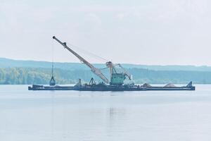 dredging boat is working to deepen the fairway on the river photo