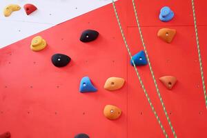 background - multi-colored climbing wall with holds and ropes photo