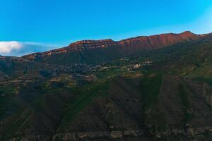 montaña paisaje con un pueblo en un Pendiente debajo un enorme rocoso cresta, gunib en daguestán foto