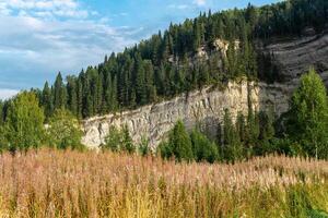 autumn landscape with wooded limestone rocks in the background in the Middle Urals, Russia photo