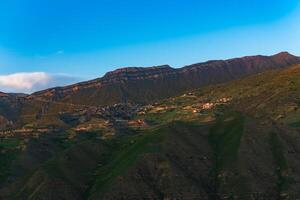 mountain landscape with a village on a slope under a huge rocky ridge, Chokh in Dagestan photo