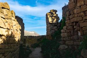 former street among the ruins in the abandoned mountain village of gamsutl in Dagestan photo