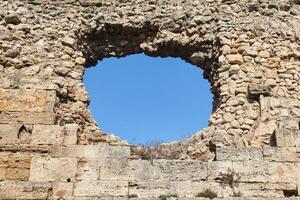 hole in an old medieval fortress wall through which the sky can be seen photo