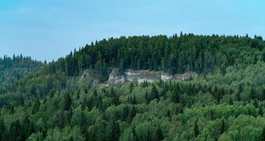 wooded hilly landscape with limestone cliff photo