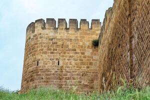 bastión de un medieval fortaleza encima un muralla descuidado con césped en contra el cielo, naryn-kala ciudadela en derbente foto