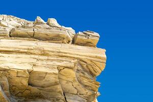 layered limestone cliff against blue sky photo