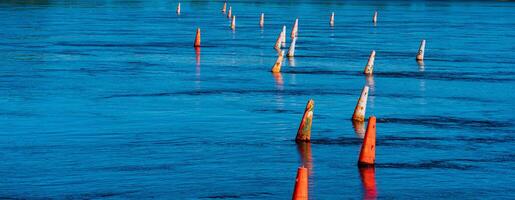 river barrier made of old faded orange buoys photo