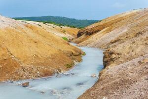 hot hydrogen sulfide stream among the banks of volcanic ash and tephra in the caldera of Golovnin volcano, Kunashir island photo