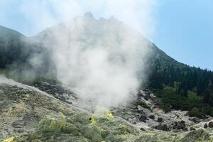 bright smoking fumarole with sulfur deposits against the background of the Mendeleev volcano peak on the island of Kunashir photo
